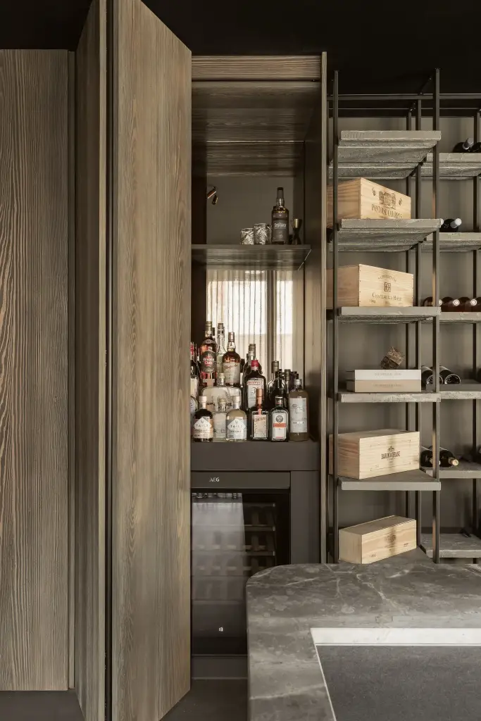 Barkast met flessen naast het wijnrek en natuursteen, met en zonder verlichting, a space that changes with the rhythm of the day, interieur Laura Calleeuw