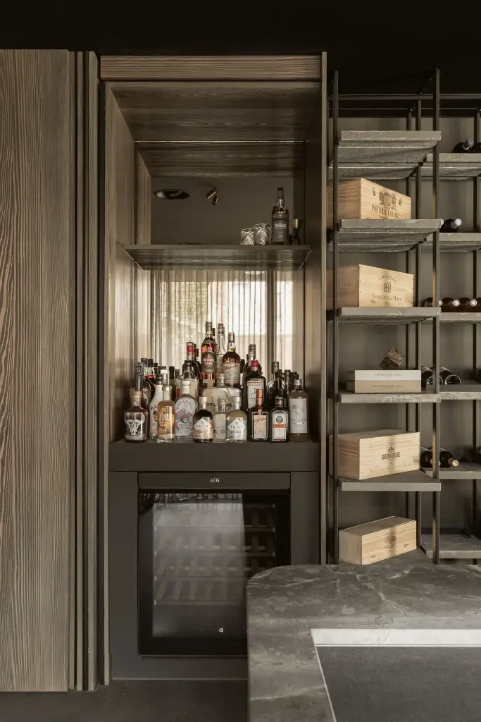 Barkast met flessen naast het wijnrek en natuursteen, met en zonder verlichting, a space that changes with the rhythm of the day, interieur Laura Calleeuw