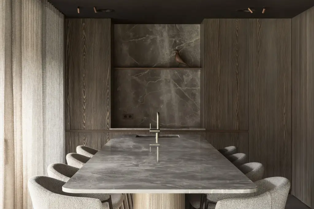 Natuurstenen eettafel met stoelen voor een houten wand met een verlichte natuurstenen nis, a space that changes with the rhythm of the day, interieur Laura Calleeuw