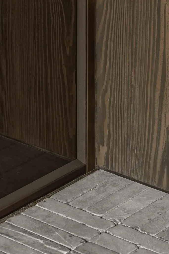 Hoek van de gebeitste houten wand op de vloer van klinkers, a space that changes with the rhythm of the day, interieur Laura Calleeuw