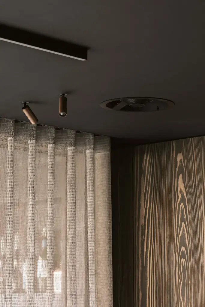Gerimpelde vitrage onder zwarte spots en een plafondventilatie, a space that changes with the rhythm of the day, interieur Laura Calleeuw