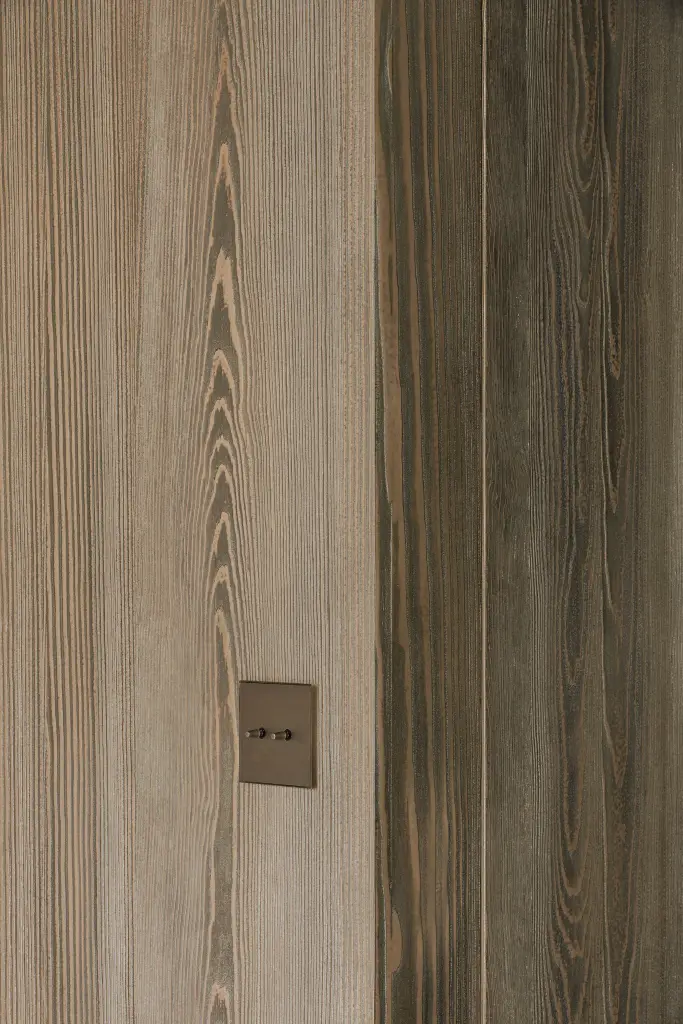 Detail van de nerf in gebeitst grenen met een bronzen schakelaar, a space that changes with the rhythm of the day, interieur Laura Calleeuw