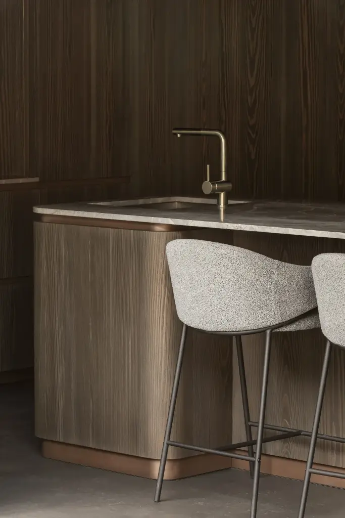 Messing kraan en spoelbak in het natuurstenen blad met een gestoffeerde barkruk, a space that changes with the rhythm of the day, interieur Laura Calleeuw