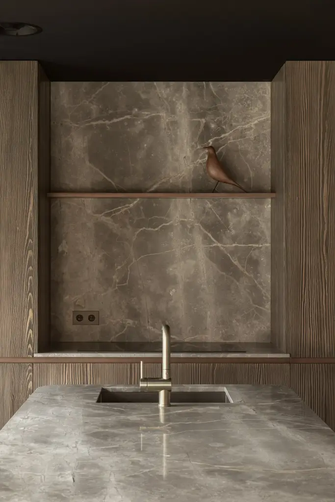 Messing kraan en spoelbak in natuursteen onder de verlichte nis, a space that changes with the rhythm of the day, interieur Laura Calleeuw