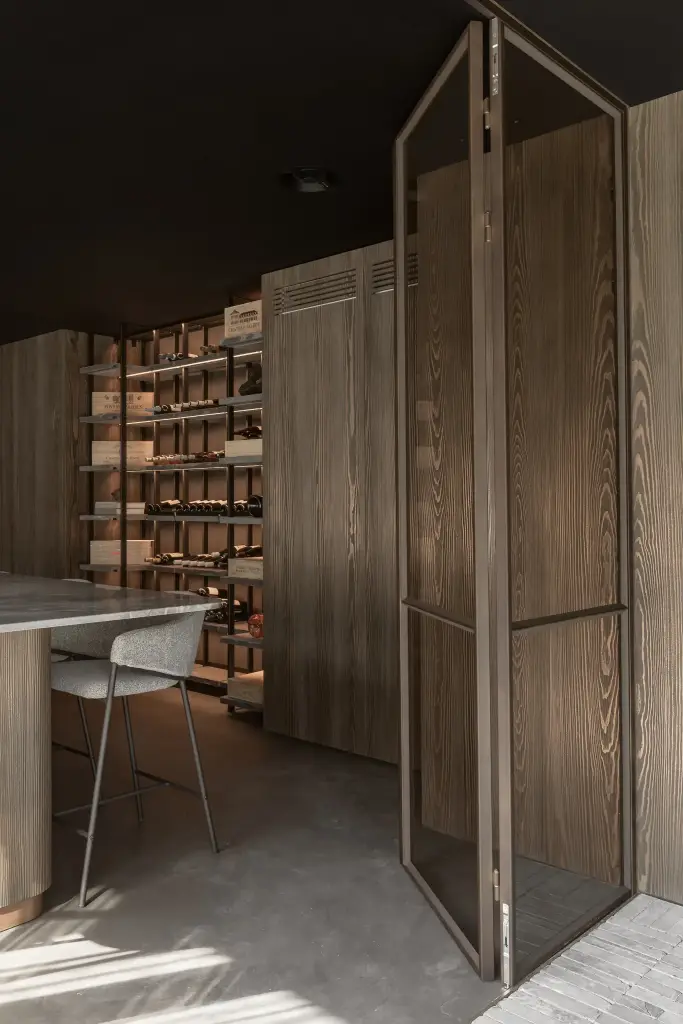 Open stalen glasdeur met zicht op de wijnrekken en de bar, a space that changes with the rhythm of the day, interieur Laura Calleeuw