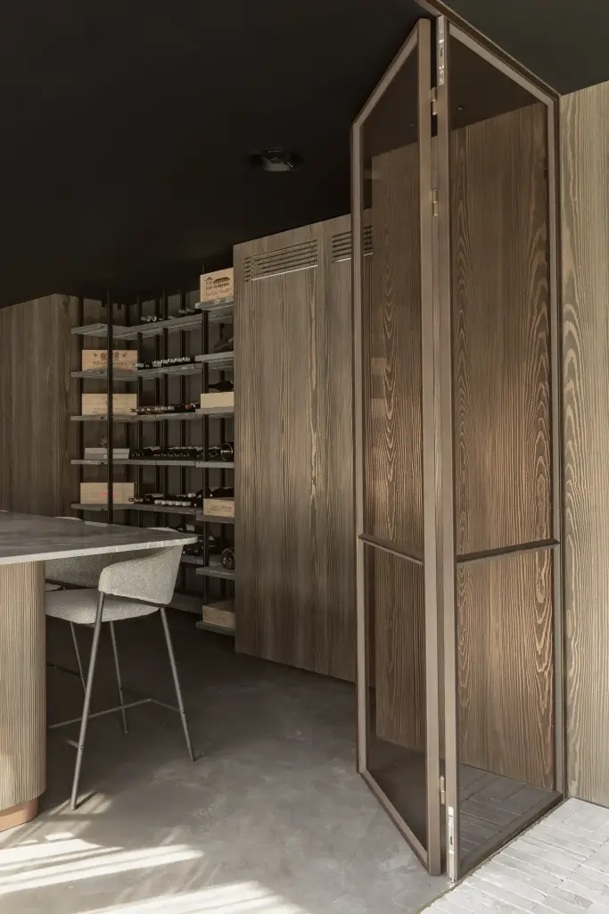 Open stalen glasdeur met zicht op de wijnrekken en de bar, a space that changes with the rhythm of the day, interieur Laura Calleeuw