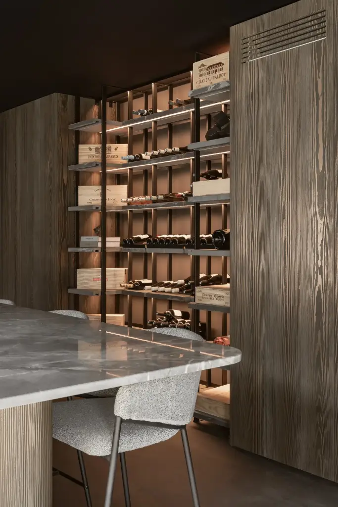 Wijnrek naast de natuurstenen tafel met barkruk en een houten kast, a space that changes with the rhythm of the day, interieur Laura Calleeuw