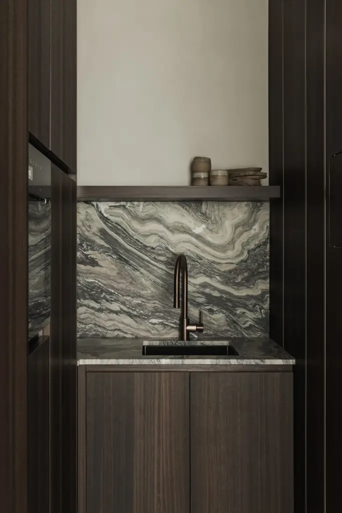 Koffiehoek met golvende marmeren achterwand, koperen kraan en een plank met aardewerk, Kantoor KBC in Ardooie, interieur Laura Calleeuw