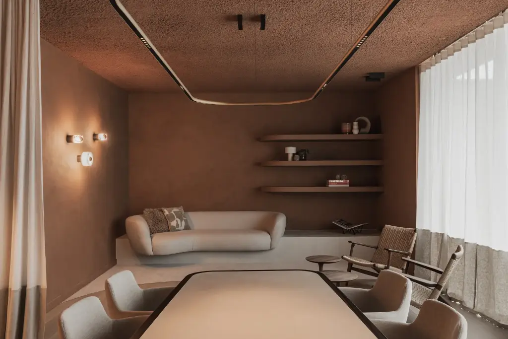 Loungehoek in een terracotta nis met sofa, houten planken en wandlampjes naast de vergadertafel, Kantoor KBC in Ardooie, interieur Laura Calleeuw