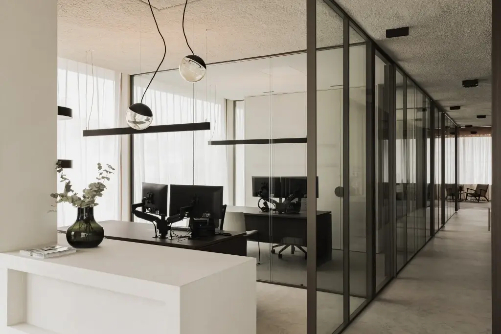 Open kantoor met glazen wanden, bolvormige hanglampen en een witte balie met plant, Kantoor KBC in Ardooie, interieur Laura Calleeuw