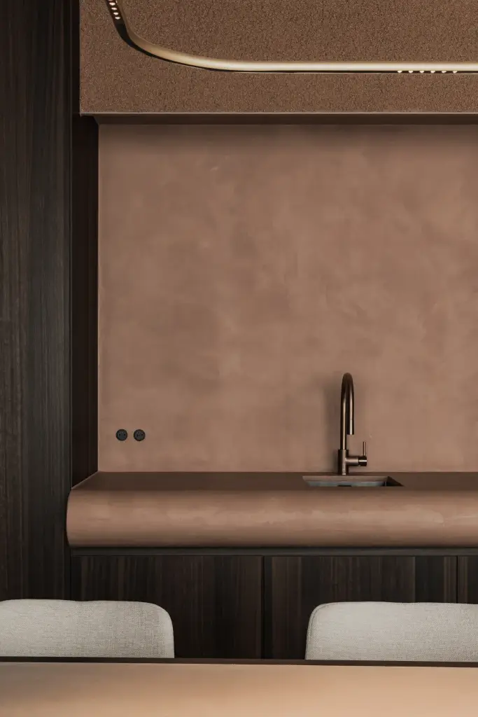 Pantry met terracotta pleisterwand, gebogen blad met spoelbak, inbouwovens en een gouden lichtlijn, Kantoor KBC in Ardooie, interieur Laura Calleeuw