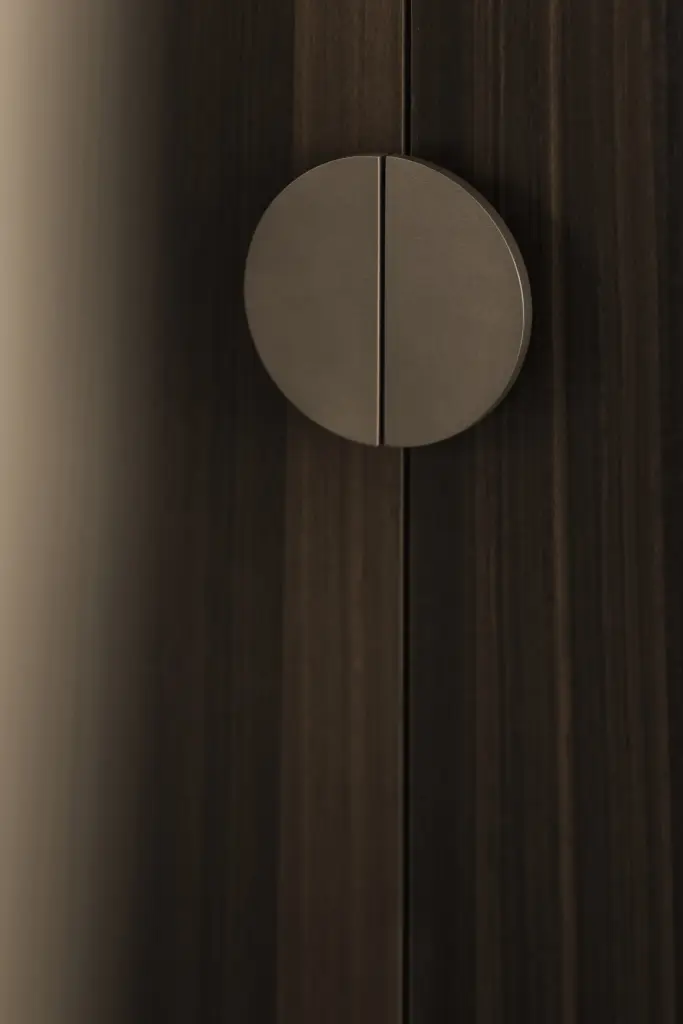 Detail van een ronde greep op een donkere houten kastdeur, Kantoor KBC in Ardooie, interieur Laura Calleeuw