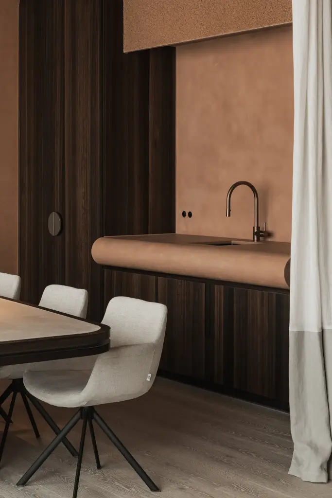 Keukenblok met gebogen blad in terracotta naast donkere houten kasten en de vergadertafel, Kantoor KBC in Ardooie, interieur Laura Calleeuw
