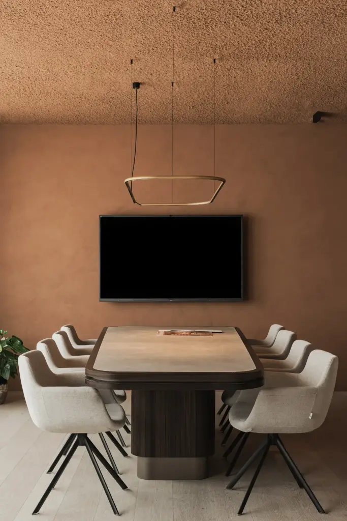 Vergaderruimte met televisie op de terracotta wand, hanglamp en ovale tafel, Kantoor KBC in Ardooie, interieur Laura Calleeuw