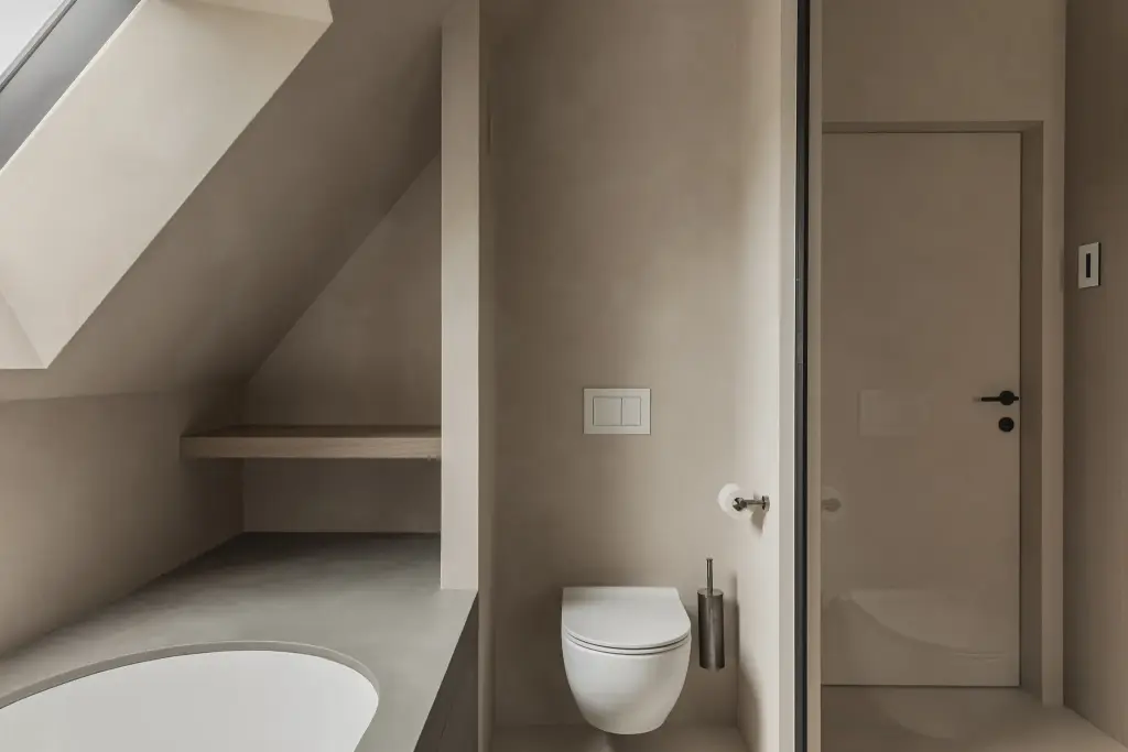 Badkamer onder het schuine dak met ligbad, hangtoilet en stalen glaswand, where architecture creates space for experience, interieur Laura Calleeuw