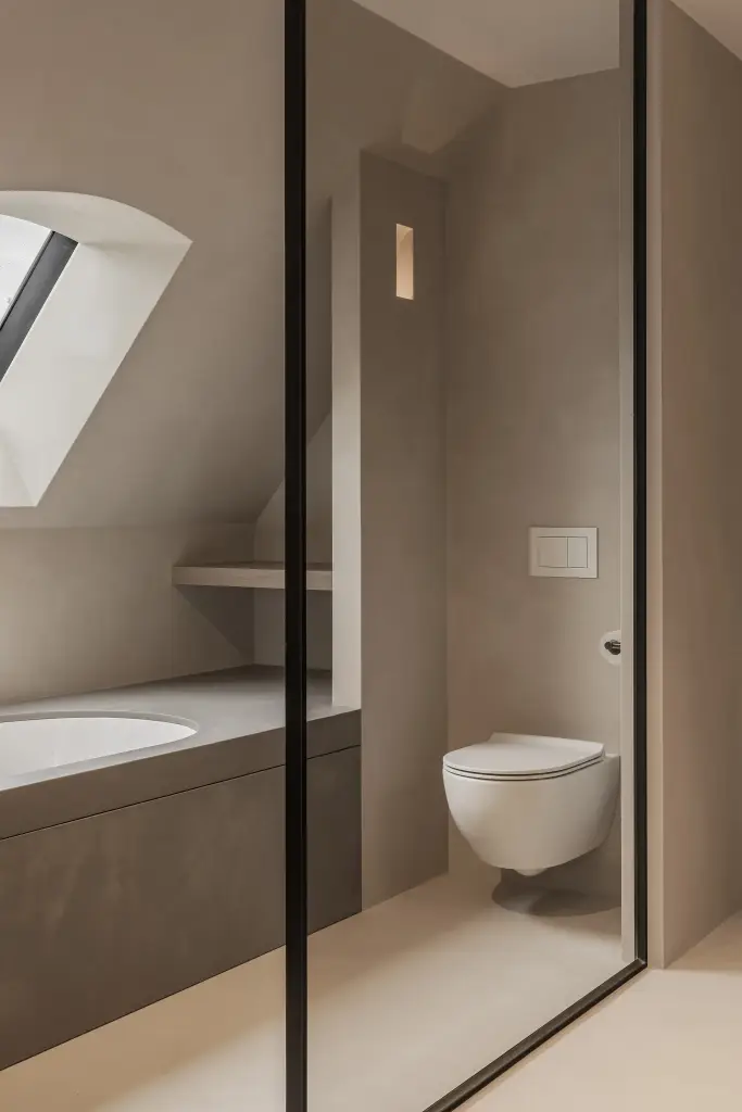 Badkamer onder het schuine dak met ligbad, hangtoilet en stalen glaswand, where architecture creates space for experience, interieur Laura Calleeuw