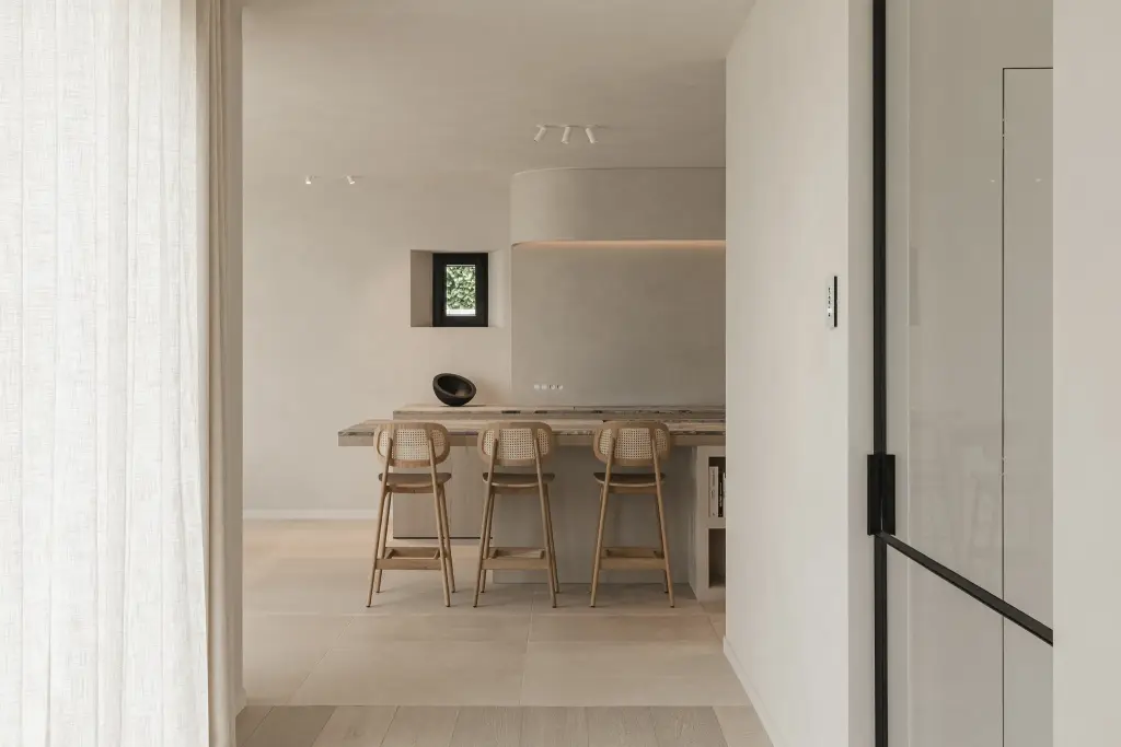 Doorkijk door een stalen deur naar de keuken met barkrukken, where architecture creates space for experience, interieur Laura Calleeuw