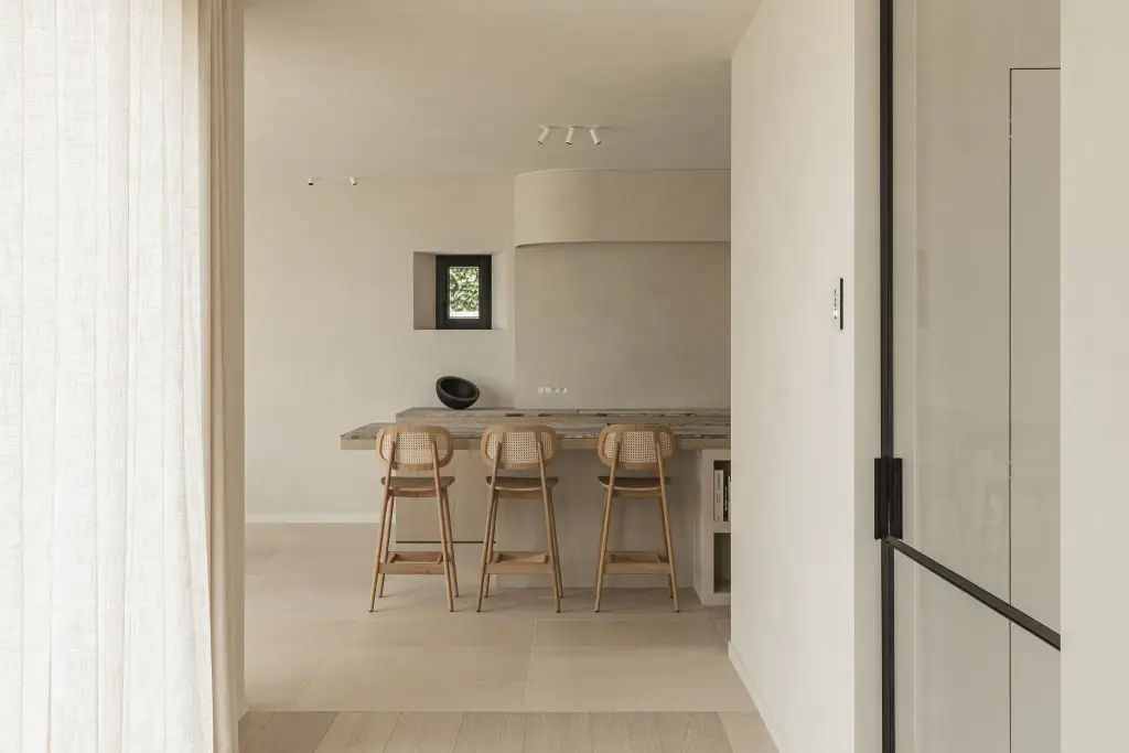 Doorkijk door een stalen deur naar de keuken met barkrukken, where architecture creates space for experience, interieur Laura Calleeuw