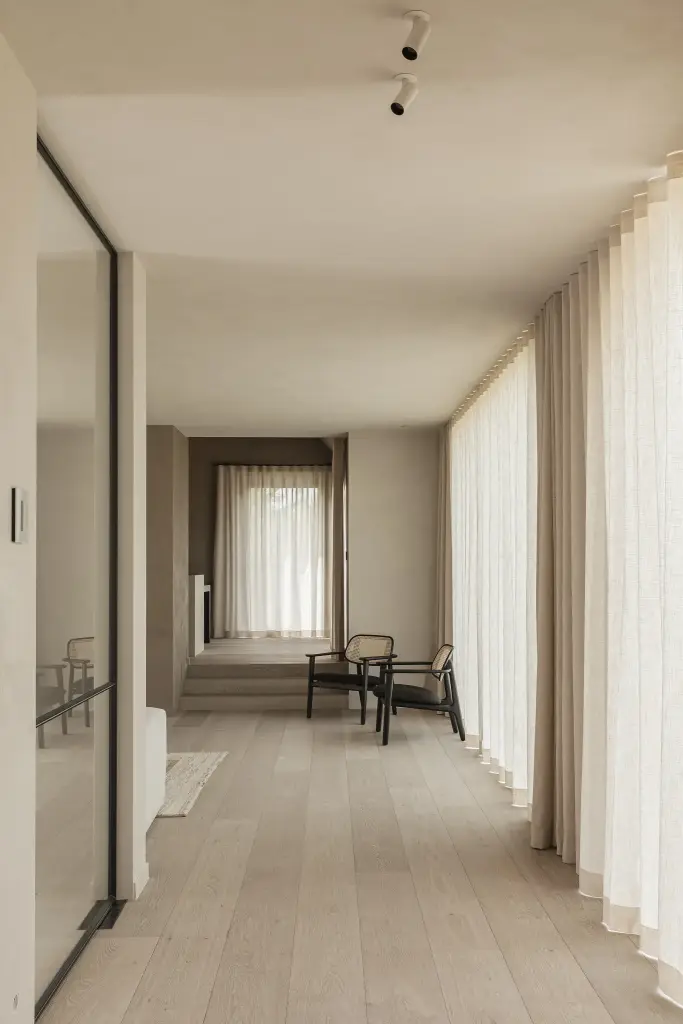 Lange woonruimte met linnen gordijnen en fauteuils op de achtergrond, where architecture creates space for experience, interieur Laura Calleeuw