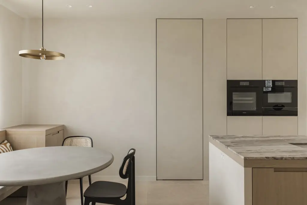 Eethoek met messing hanglamp, ronde tafel en kast met inbouwovens, where architecture creates space for experience, interieur Laura Calleeuw