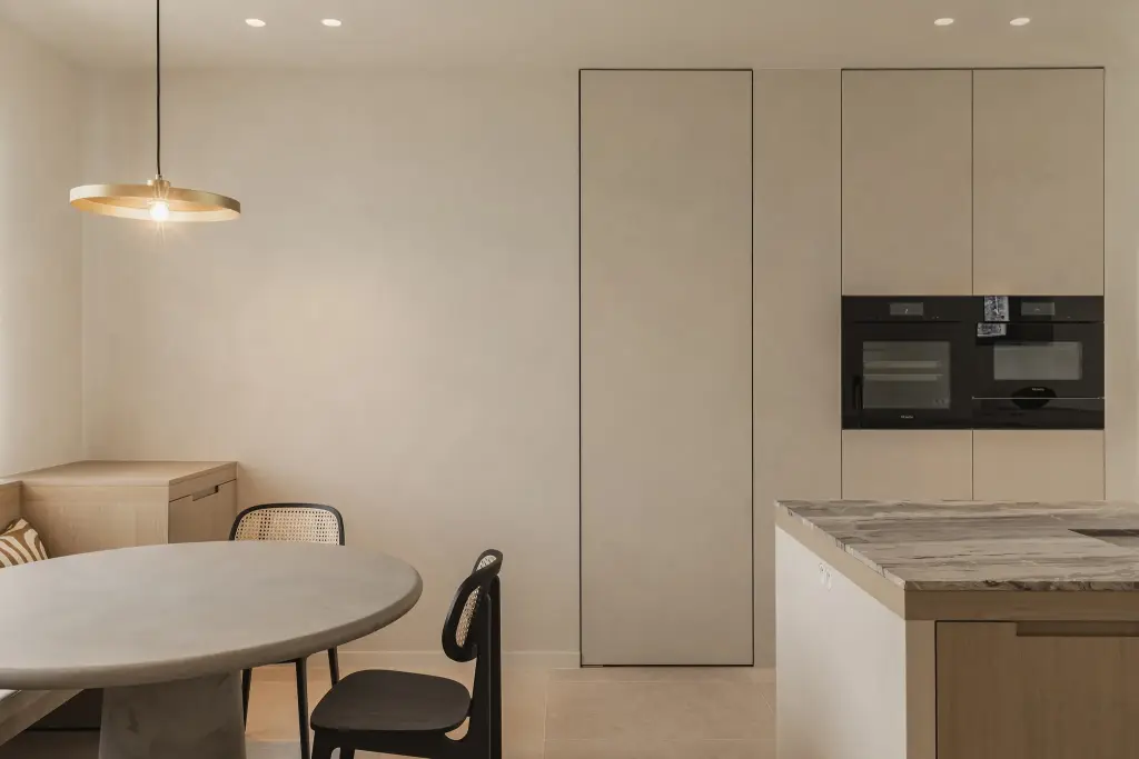 Eethoek met messing hanglamp, ronde tafel en kast met inbouwovens, where architecture creates space for experience, interieur Laura Calleeuw