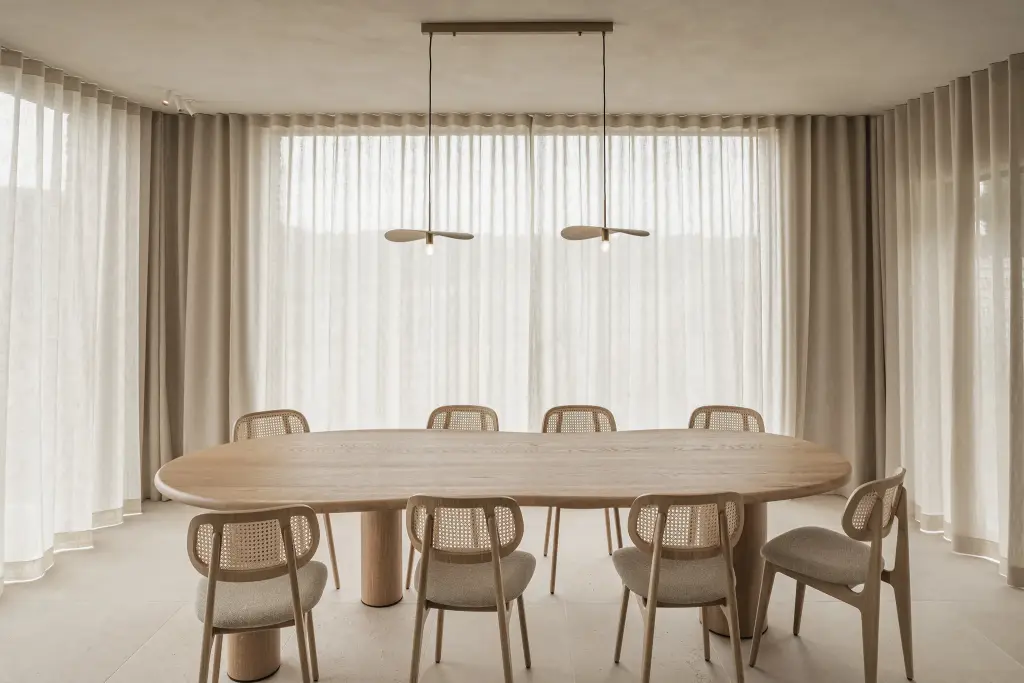 Eetruimte met ovale eiken tafel, rotan stoelen en lange gordijnen, where architecture creates space for experience, interieur Laura Calleeuw