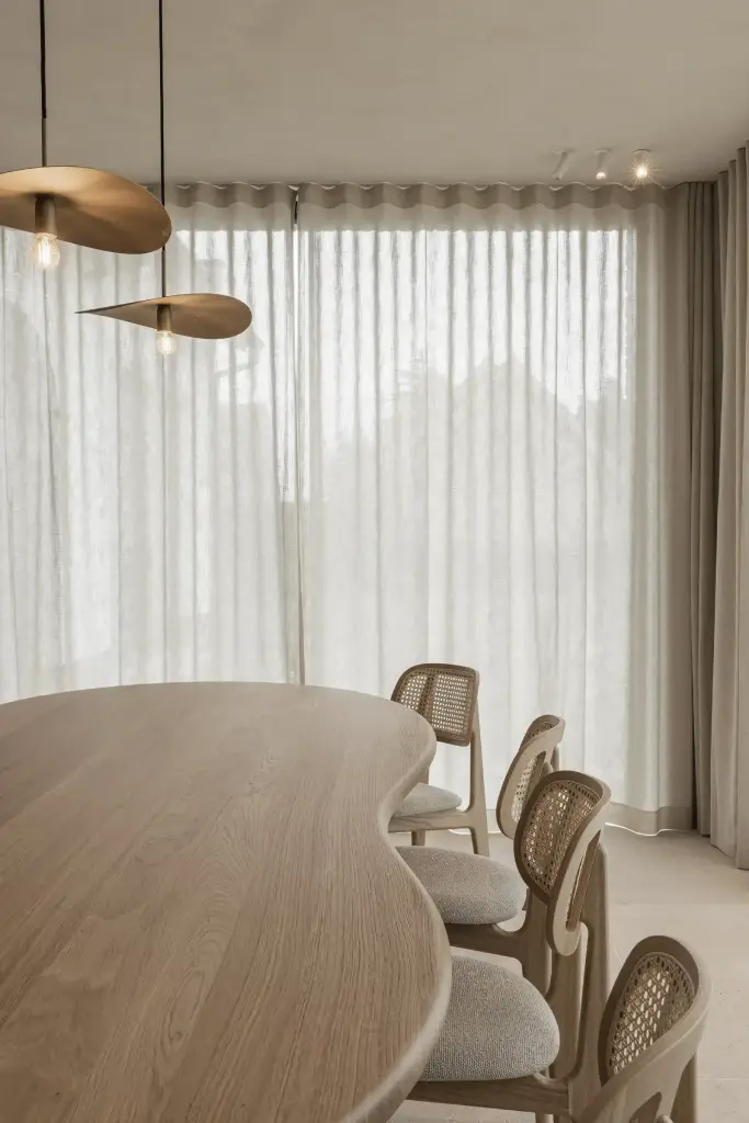 Rotan eetstoelen aan de ovale eiken tafel voor het gordijn, where architecture creates space for experience, interieur Laura Calleeuw