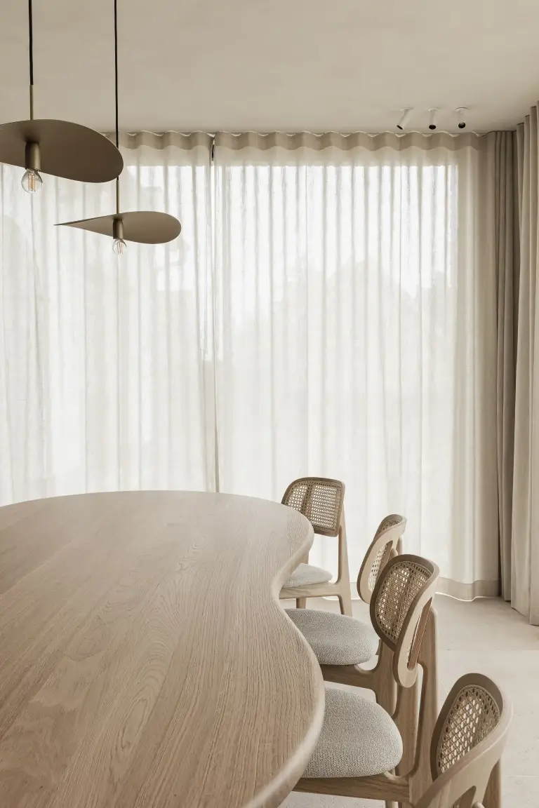Rotan eetstoelen aan de ovale eiken tafel voor het gordijn, where architecture creates space for experience, interieur Laura Calleeuw