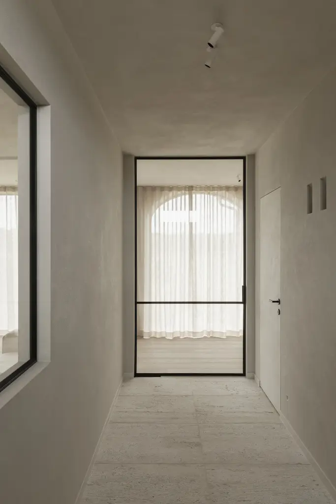 Gang met zwarte stalen glaswand en boogvormig raam met linnen gordijn, where architecture creates space for experience, interieur Laura Calleeuw