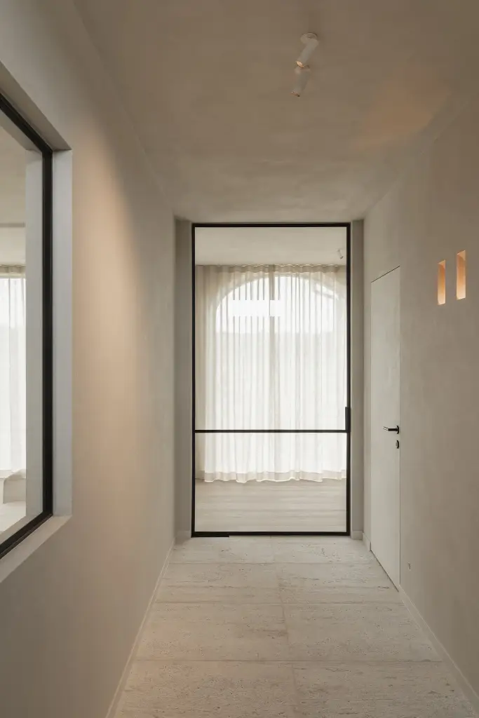 Gang met zwarte stalen glaswand en boogvormig raam met linnen gordijn, where architecture creates space for experience, interieur Laura Calleeuw