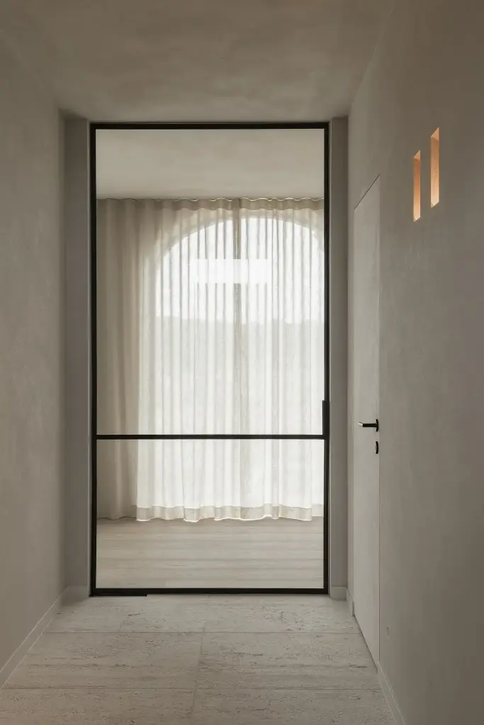 Gang met zwarte stalen glaswand en boogvormig raam met linnen gordijn, where architecture creates space for experience, interieur Laura Calleeuw