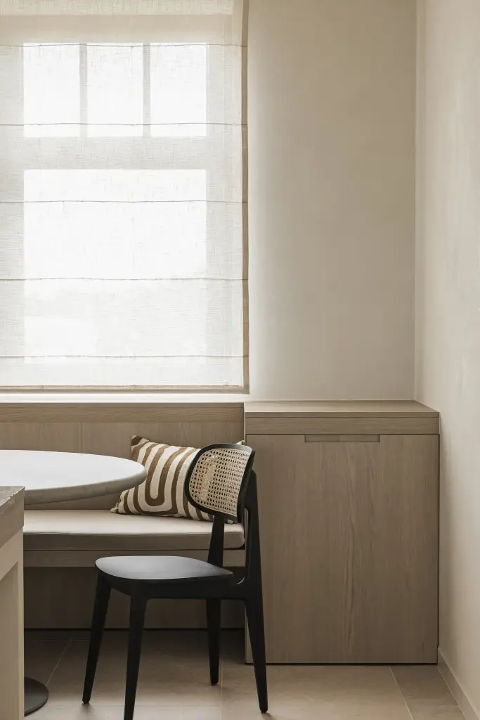 Keuken met travertijn eiland, inbouwovens en eethoek met zitbank onder het raam, where architecture creates space for experience, interieur Laura Calleeuw