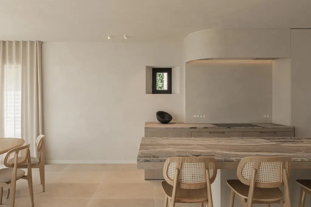 Keuken met travertijn eiland en rotan stoelen, where architecture creates space for experience, interieur Laura Calleeuw