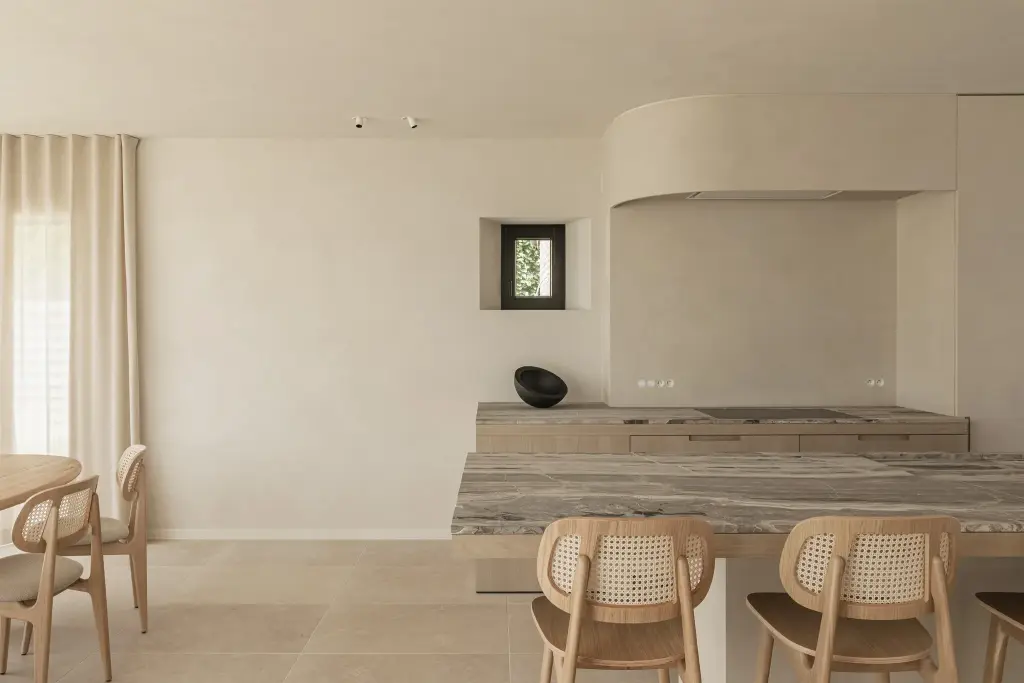 Keuken met travertijn eiland en rotan stoelen, where architecture creates space for experience, interieur Laura Calleeuw