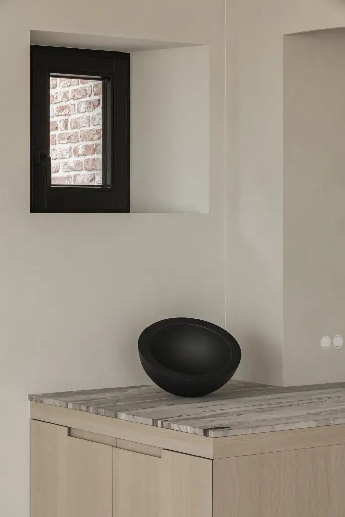 Keuken met kookplaat, klein venster in microcement nis en zwarte schaal, where architecture creates space for experience, interieur Laura Calleeuw