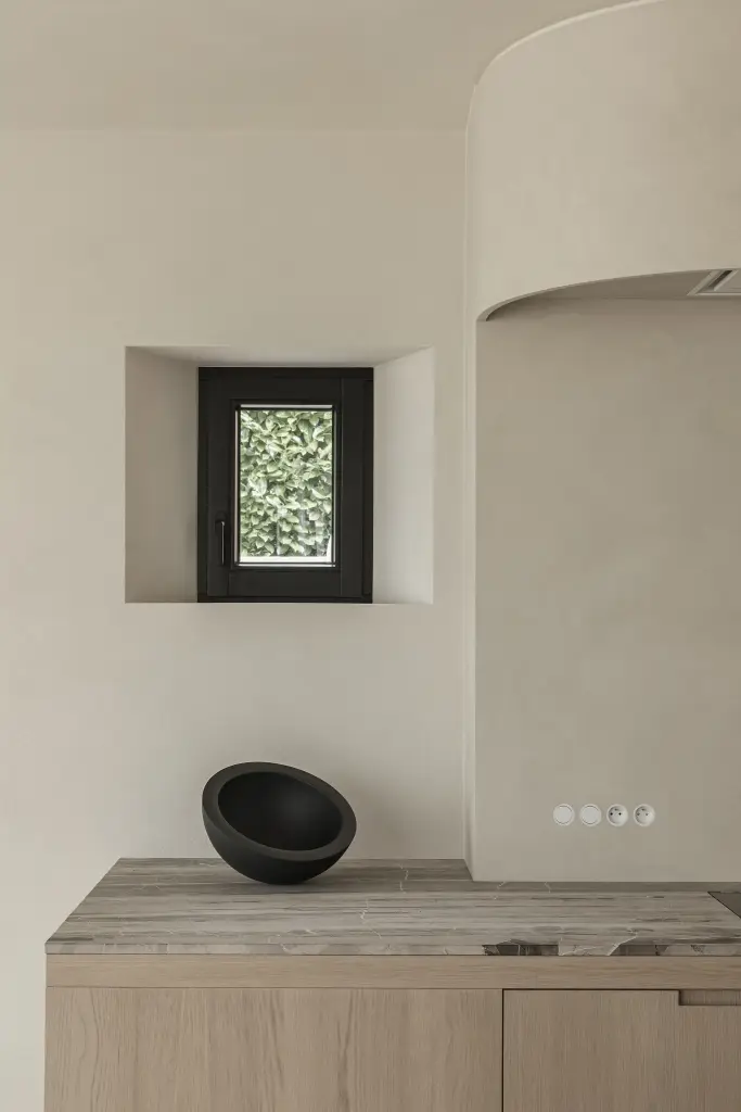 Keuken met kookplaat, klein venster in microcement nis en zwarte schaal, where architecture creates space for experience, interieur Laura Calleeuw