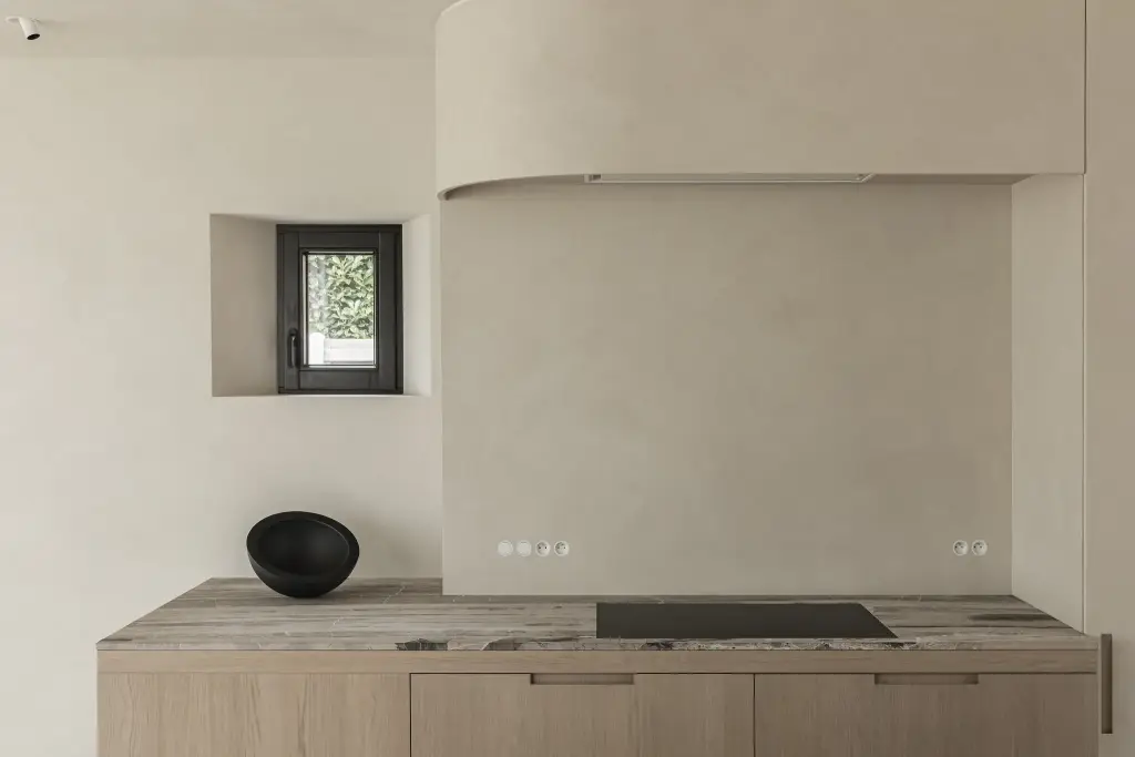 Keuken met kookplaat, klein venster in microcement nis en zwarte schaal, where architecture creates space for experience, interieur Laura Calleeuw