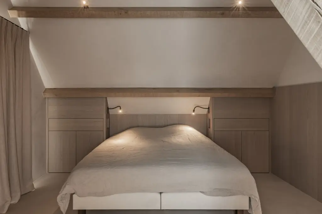 Slaapkamer onder het dak met eikenhouten balk, bed en leeslampjes, where architecture creates space for experience, interieur Laura Calleeuw