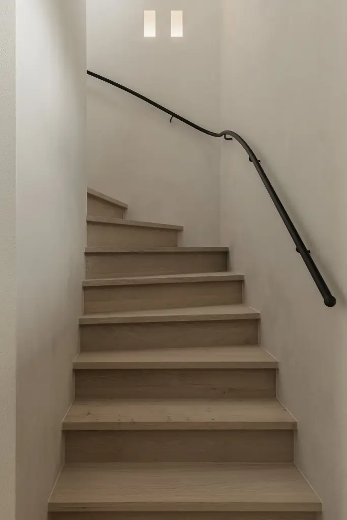 Trap met eikenhouten treden en gebogen zwarte trapleuning in microcement, where architecture creates space for experience, interieur Laura Calleeuw