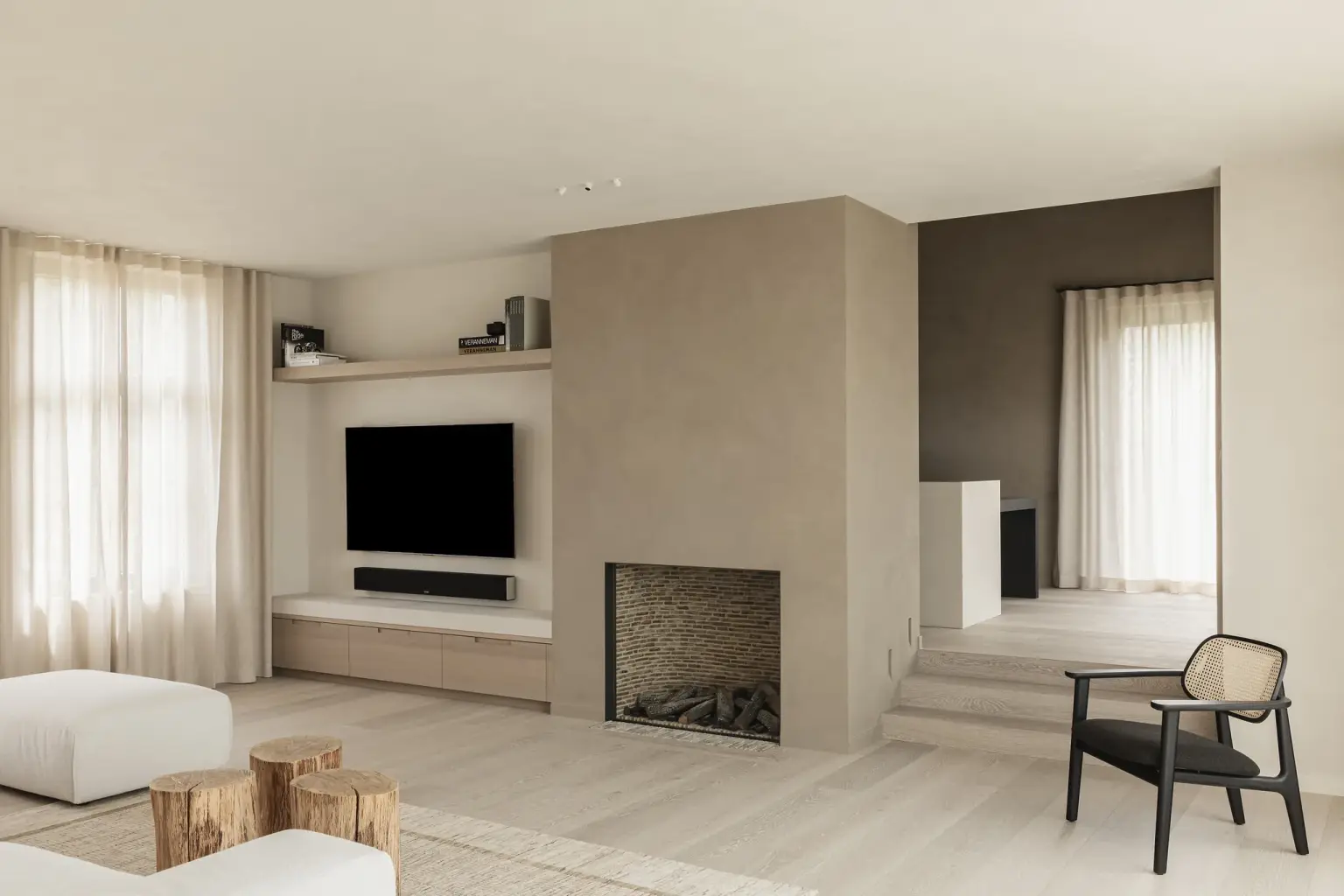 Woonkamer met gashaard in microcement schouw, televisiewand en rotan fauteuil, where architecture creates space for experience, interieur Laura Calleeuw