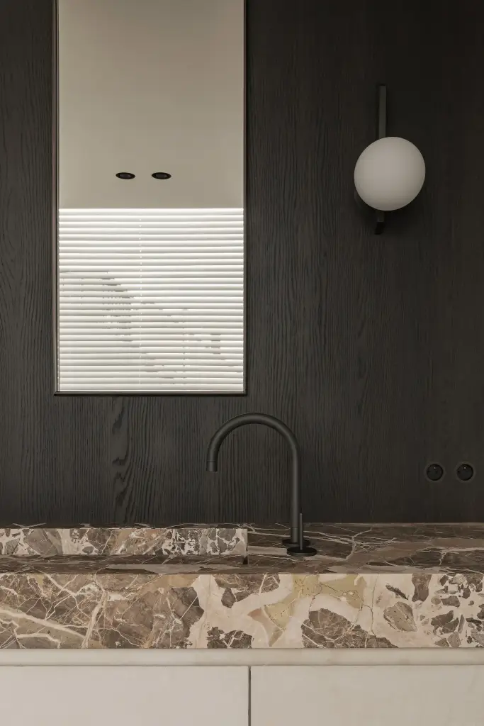Badkamer met marmeren wastafel, bolvormige wandlamp en donker eiken paneel, Kijkwoning in Erpe-Mere, interieur Laura Calleeuw