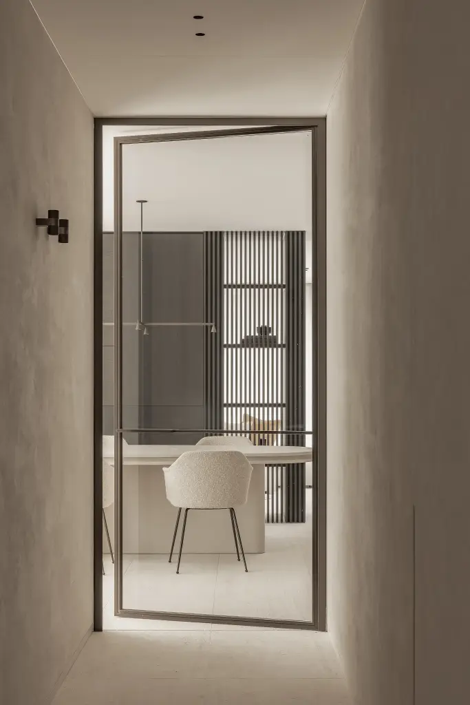 Doorkijk naar de eetruimte door een stalen deur in een microcement gang, Kijkwoning in Erpe-Mere, interieur Laura Calleeuw