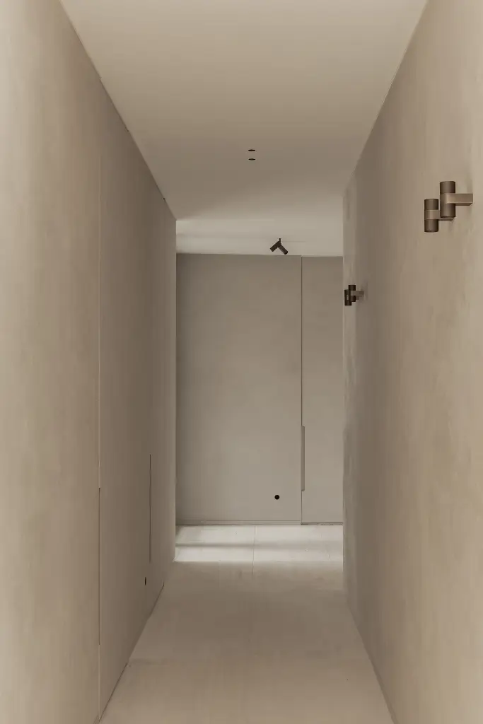 Gang met microcement wanden en vloer en een wandlicht, Kijkwoning in Erpe-Mere, interieur Laura Calleeuw