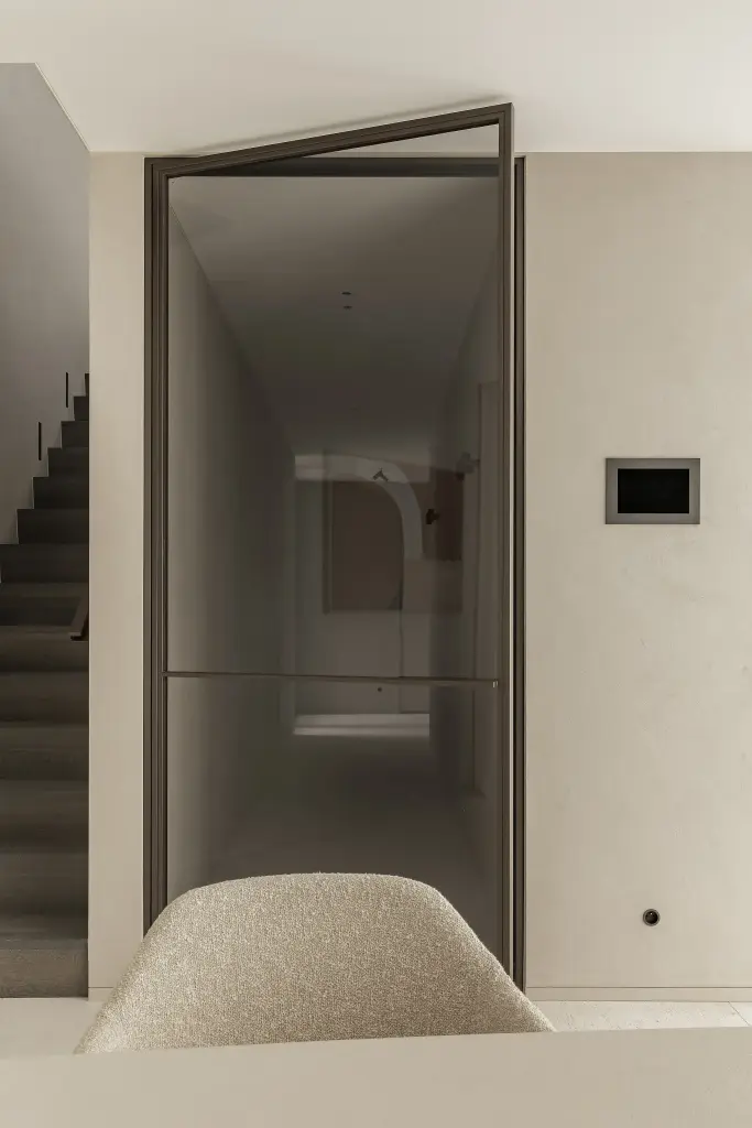 Doorkijk door een stalen deur naar de trap en eetruimte, Kijkwoning in Erpe-Mere, interieur Laura Calleeuw