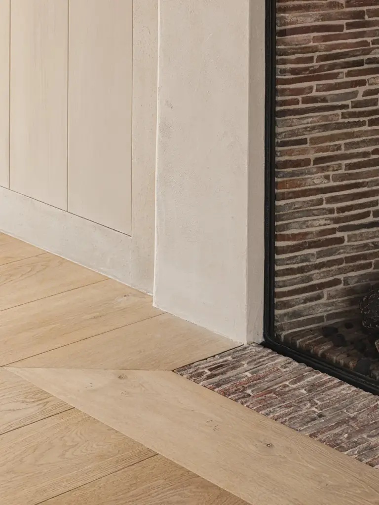 Bakstenen haardwand en kastdeuren naast het brede eiken parket, Landelijke woning in Torhout, interieur Laura Calleeuw