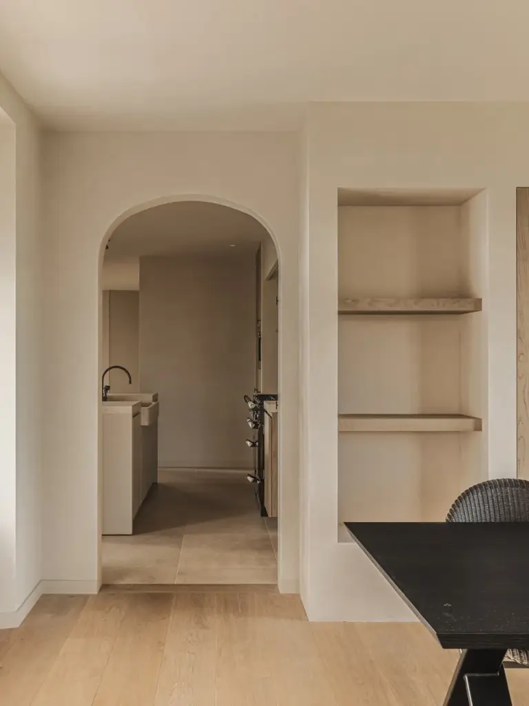 Doorkijk door een boogopening naar de keuken, met een nis met eiken planken en de eethoek, Landelijke woning in Torhout, interieur Laura Calleeuw