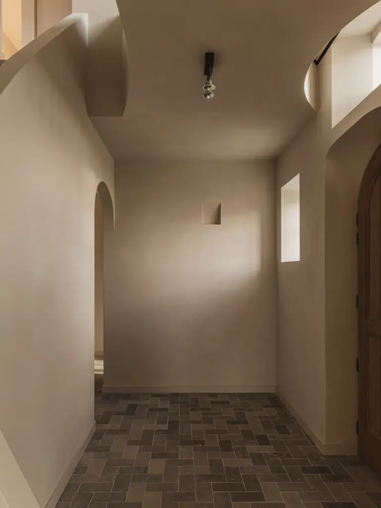 Gang met boogopeningen in kalkpleister en een vloer van klinkers, Landelijke woning in Torhout, interieur Laura Calleeuw