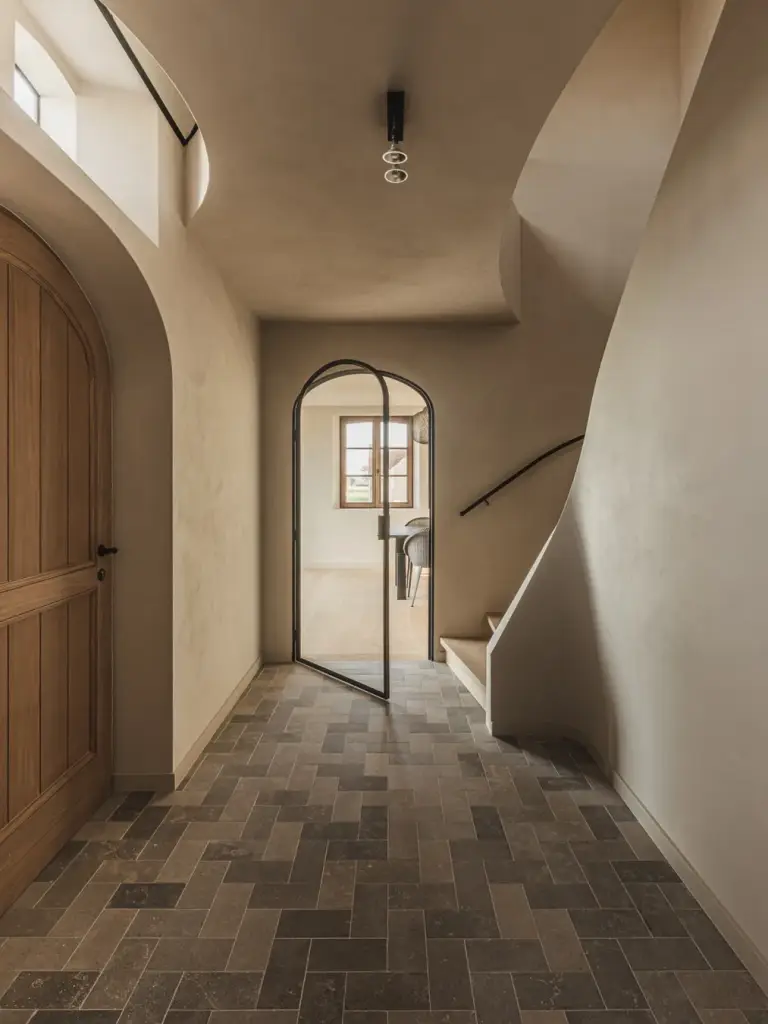 Inkomhal met houten boogdeur, glazen boogdeur, gebogen trap en klinkervloer, Landelijke woning in Torhout, interieur Laura Calleeuw