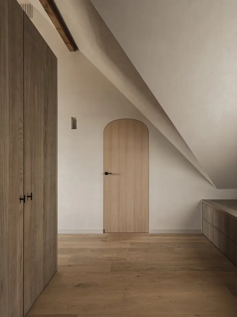 Kastenwand in gebeitst eiken onder de dakhelling met een zichtbare houten balk, Landelijke woning in Torhout, interieur Laura Calleeuw