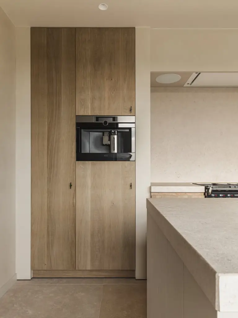 Keukenkolom in eikenhout met inbouwkoffiemachine naast het natuurstenen eiland, Landelijke woning in Torhout, interieur Laura Calleeuw